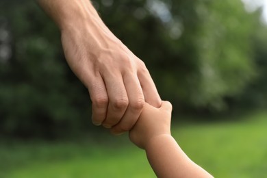 Daughter holding father's hand in park, closeup. Happy family