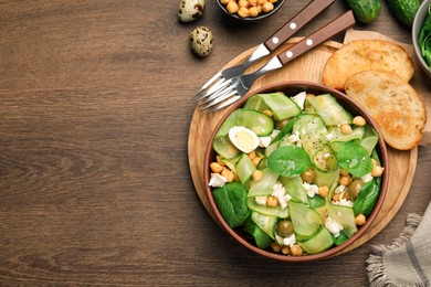 Delicious cucumber salad and toasted bread served on wooden table, flat lay. Space for text