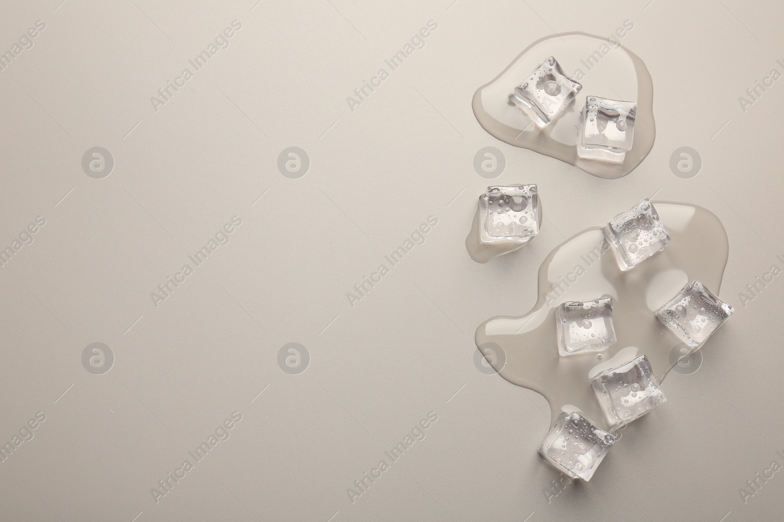 Photo of Melting ice cubes and water drops on light grey background, flat lay. Space for text