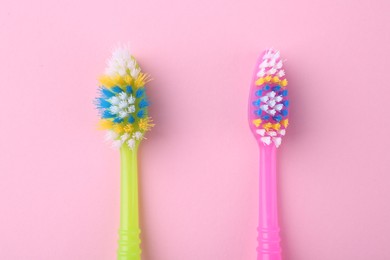 Photo of Colorful plastic toothbrushes on pink background, flat lay