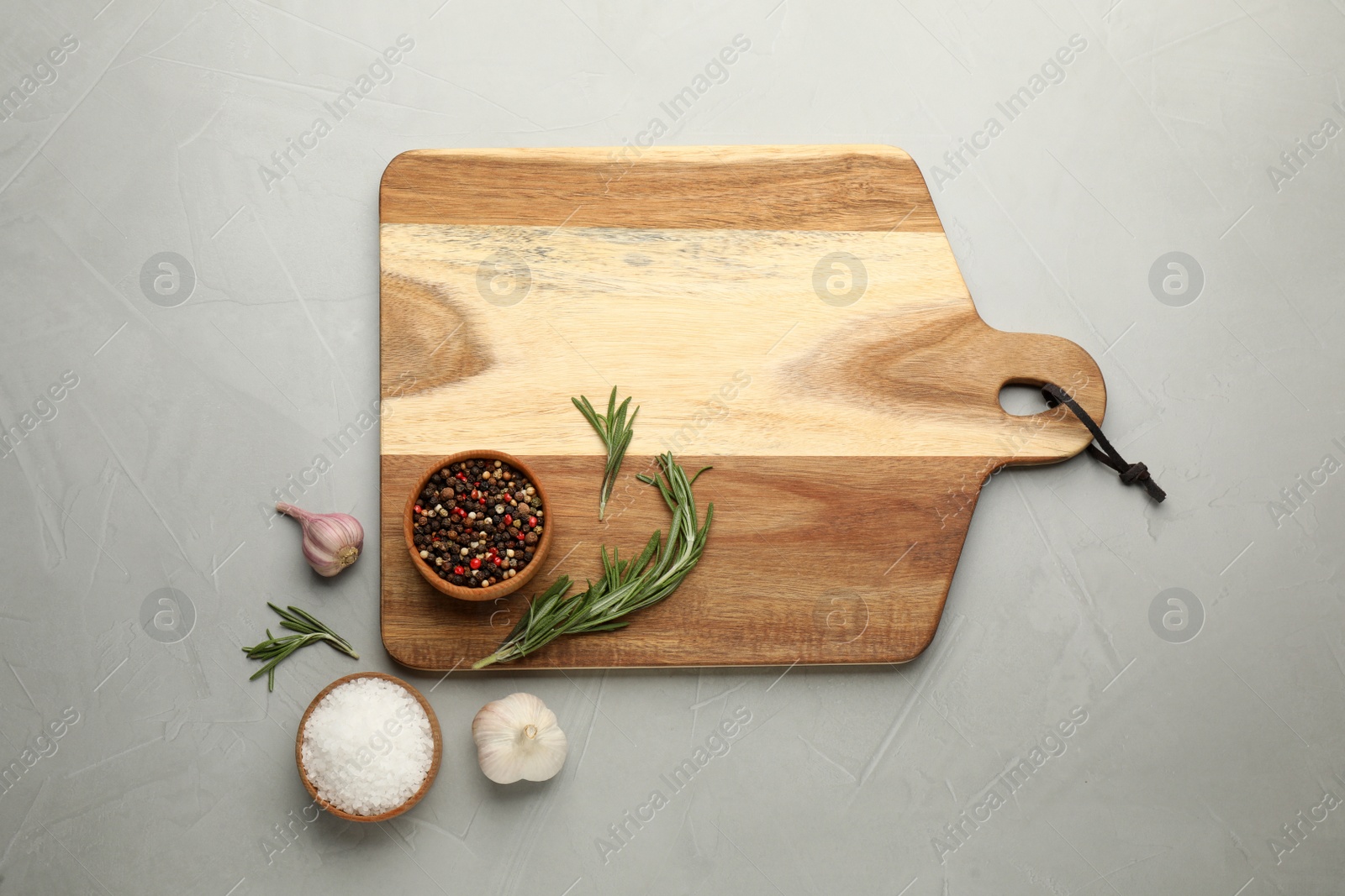 Photo of Flat lay composition with wooden cutting board and ingredients on light grey table. Cooking utensil