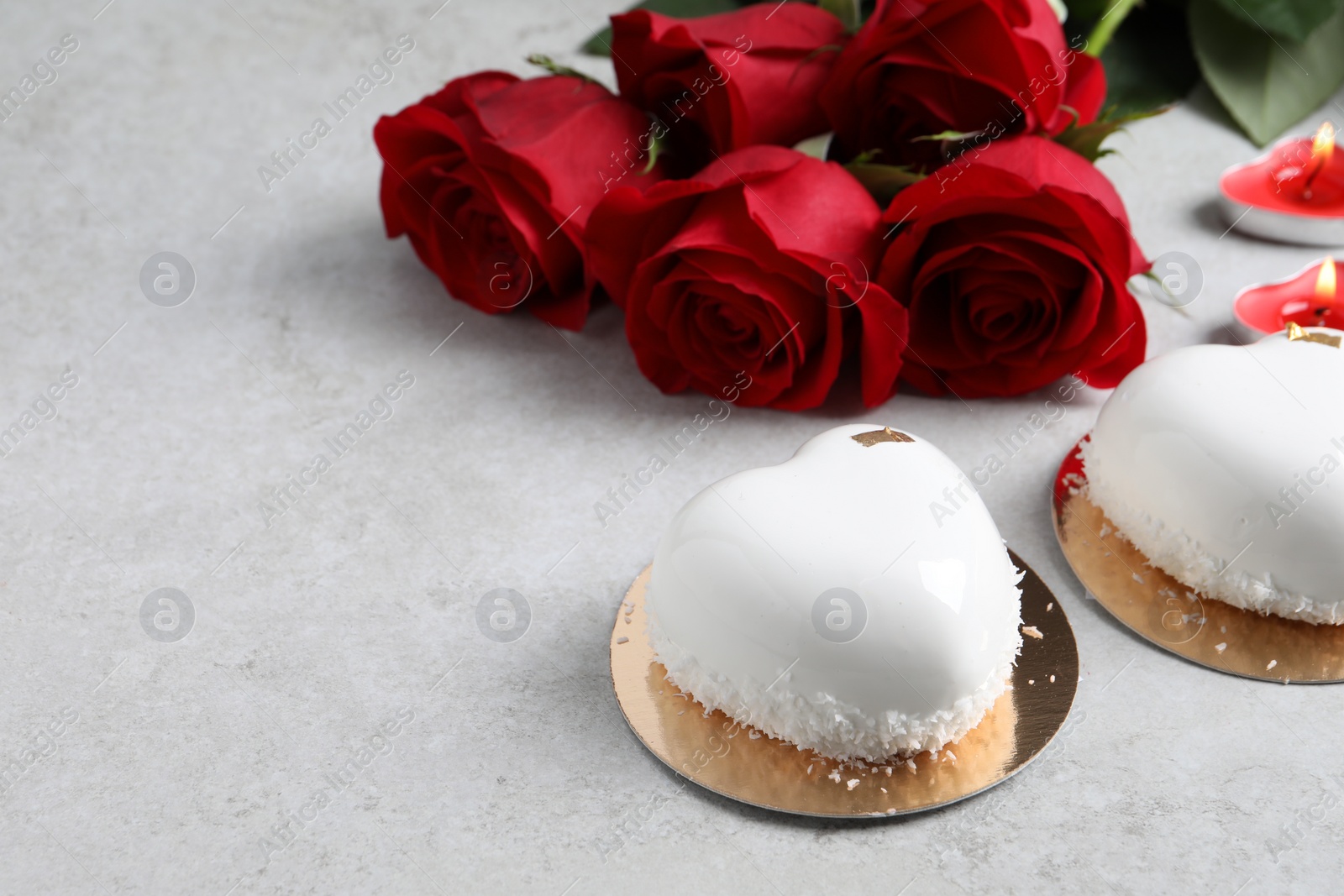 Photo of St. Valentine's Day. Delicious heart shaped cakes and roses on light table. Space for text