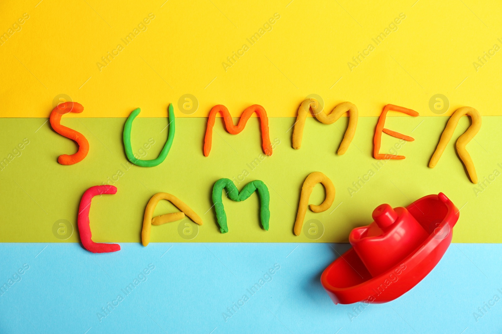 Photo of Words SUMMER CAMP made from modelling clay and plastic boat on color background, top view