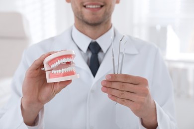 Dentist holding jaws model and tools in clinic, closeup