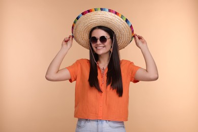 Photo of Young woman in Mexican sombrero hat and sunglasses on beige background