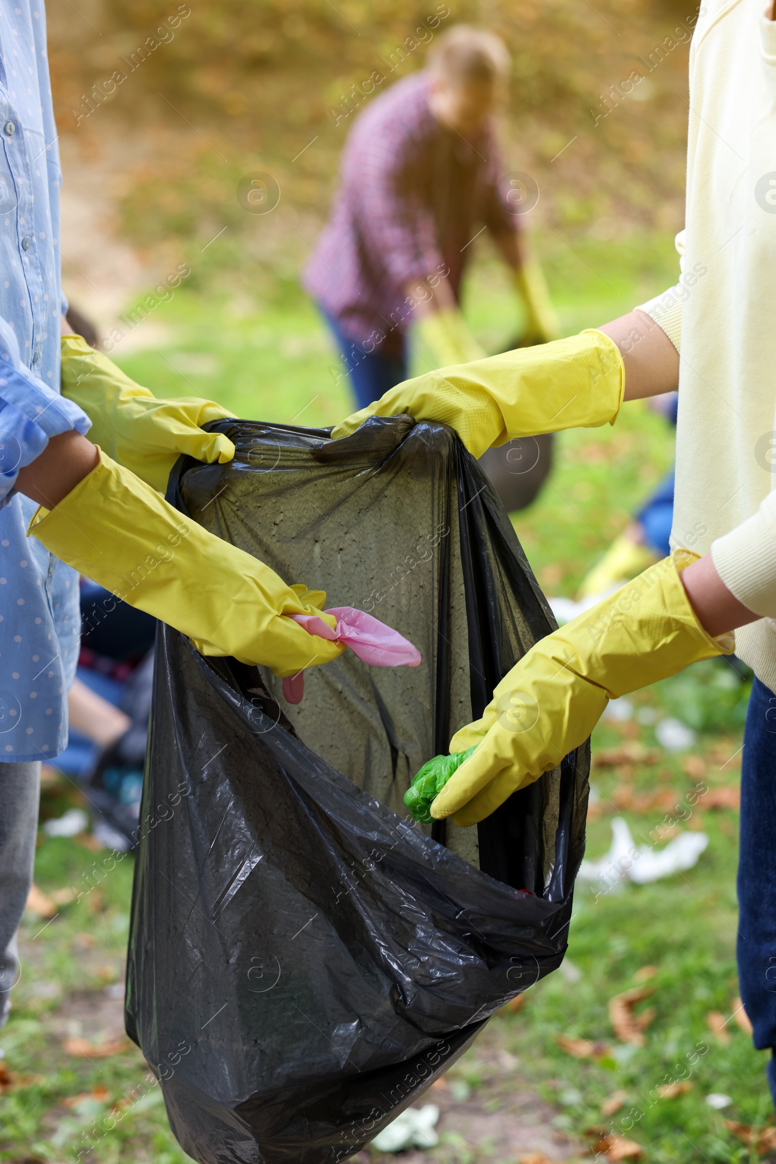 Photo of Women with plastic bag collecting garbage in park, closeup