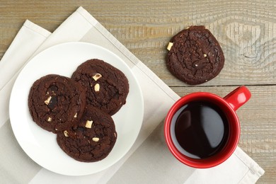Tasty chocolate cookies and cup of coffee on wooden table, flat lay