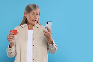 Photo of Worried woman with credit card and smartphone on light blue background, space for text. Be careful - fraud