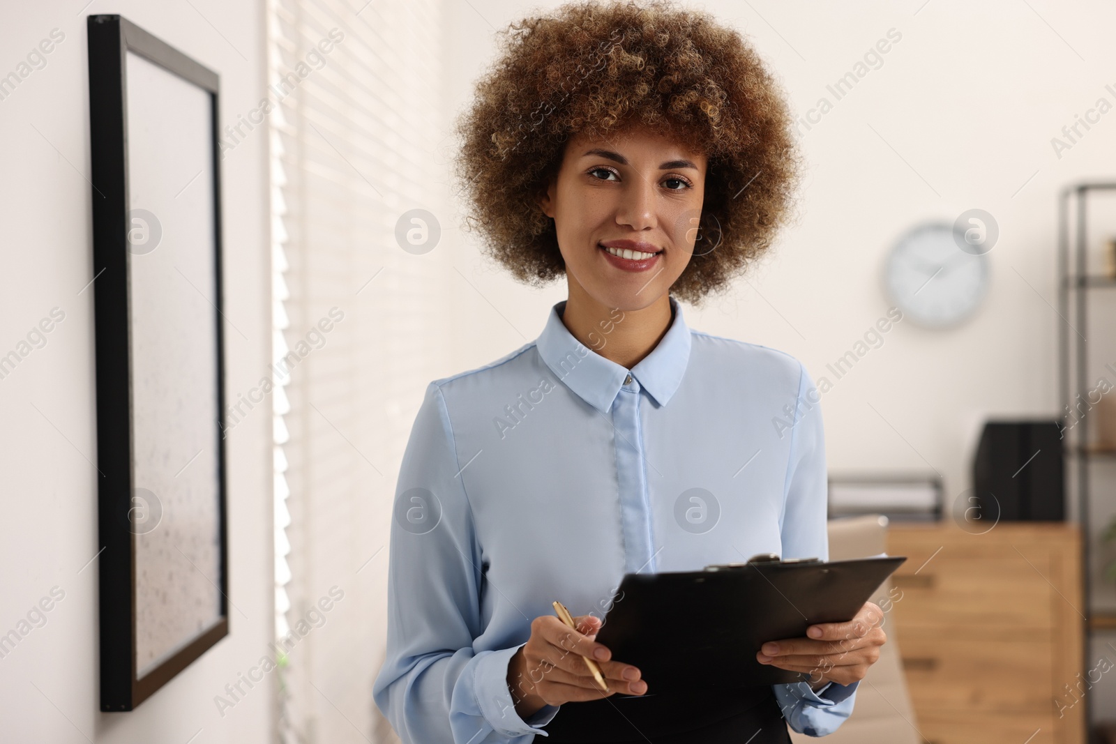 Photo of Happy notary with clipboard and pen in office