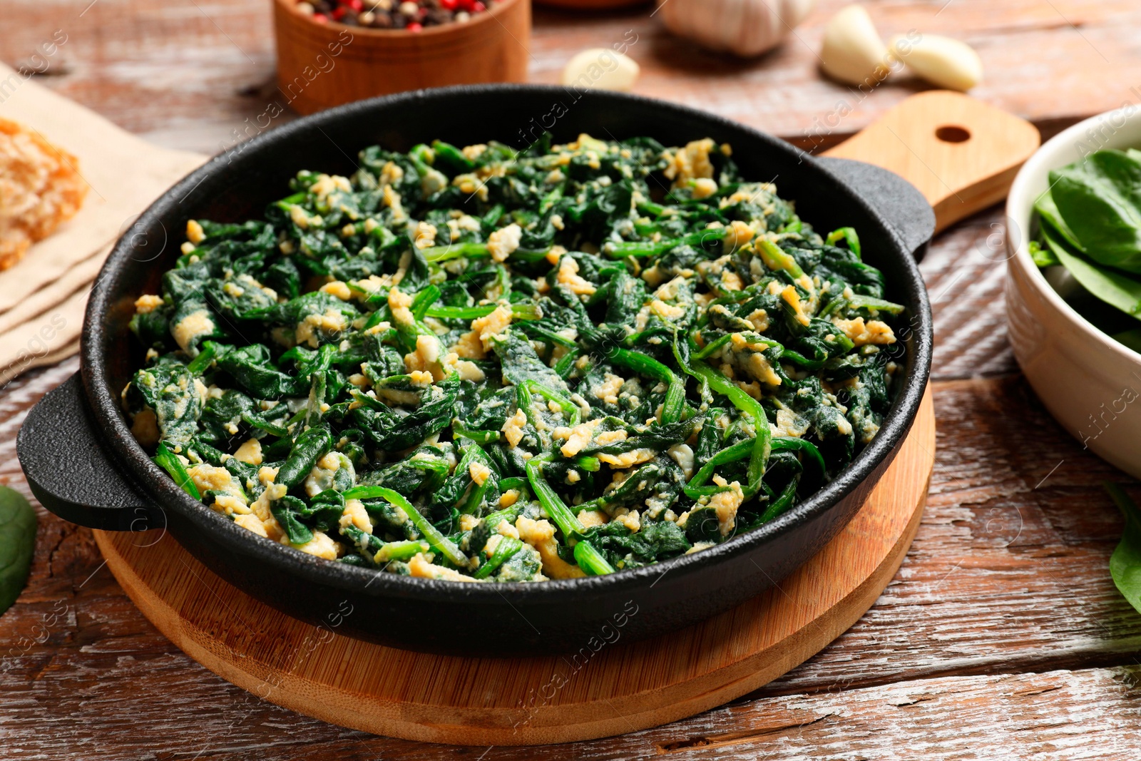 Photo of Tasty spinach dip with eggs in dish served on wooden table, closeup