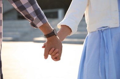 Couple holding hands together outdoors on summer day, closeup