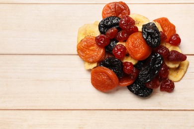 Photo of Mix of delicious dried fruits on white wooden table, top view. Space for text