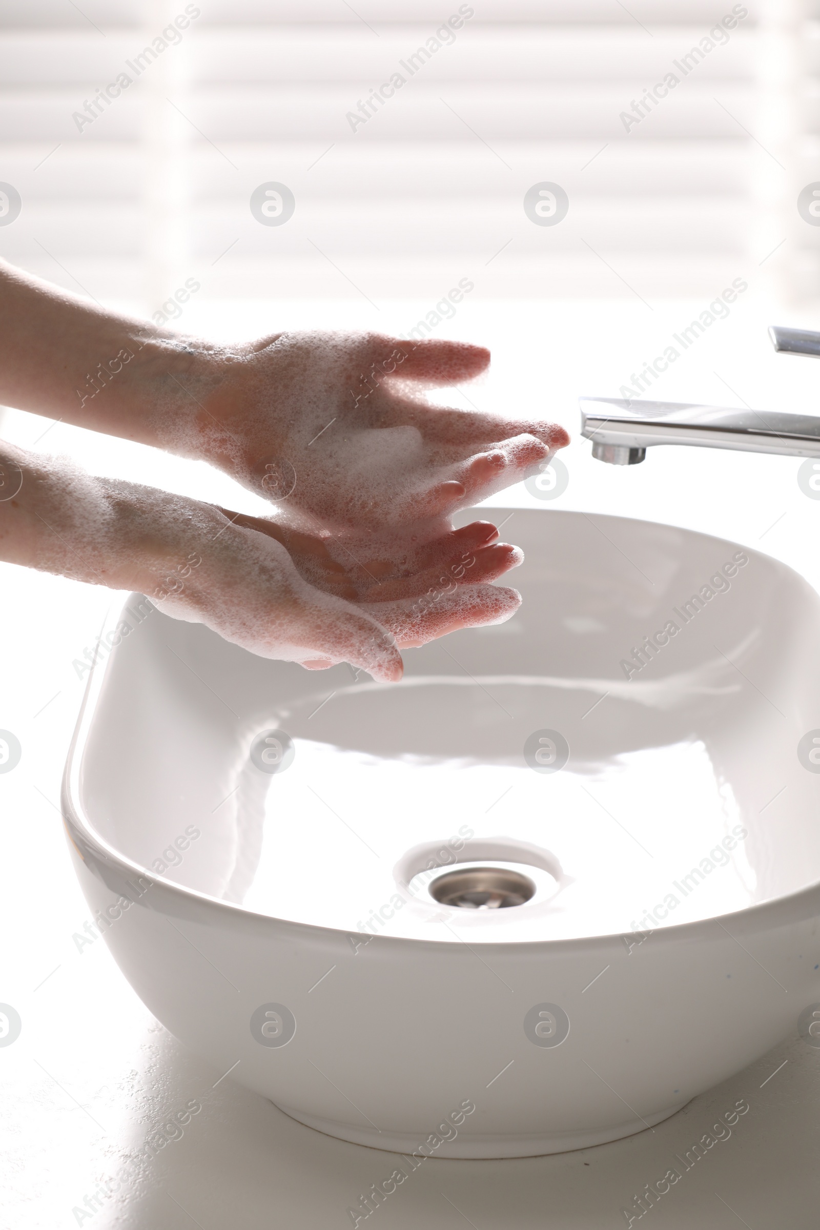 Photo of Woman washing hands with cleansing foam near sink in bathroom, closeup