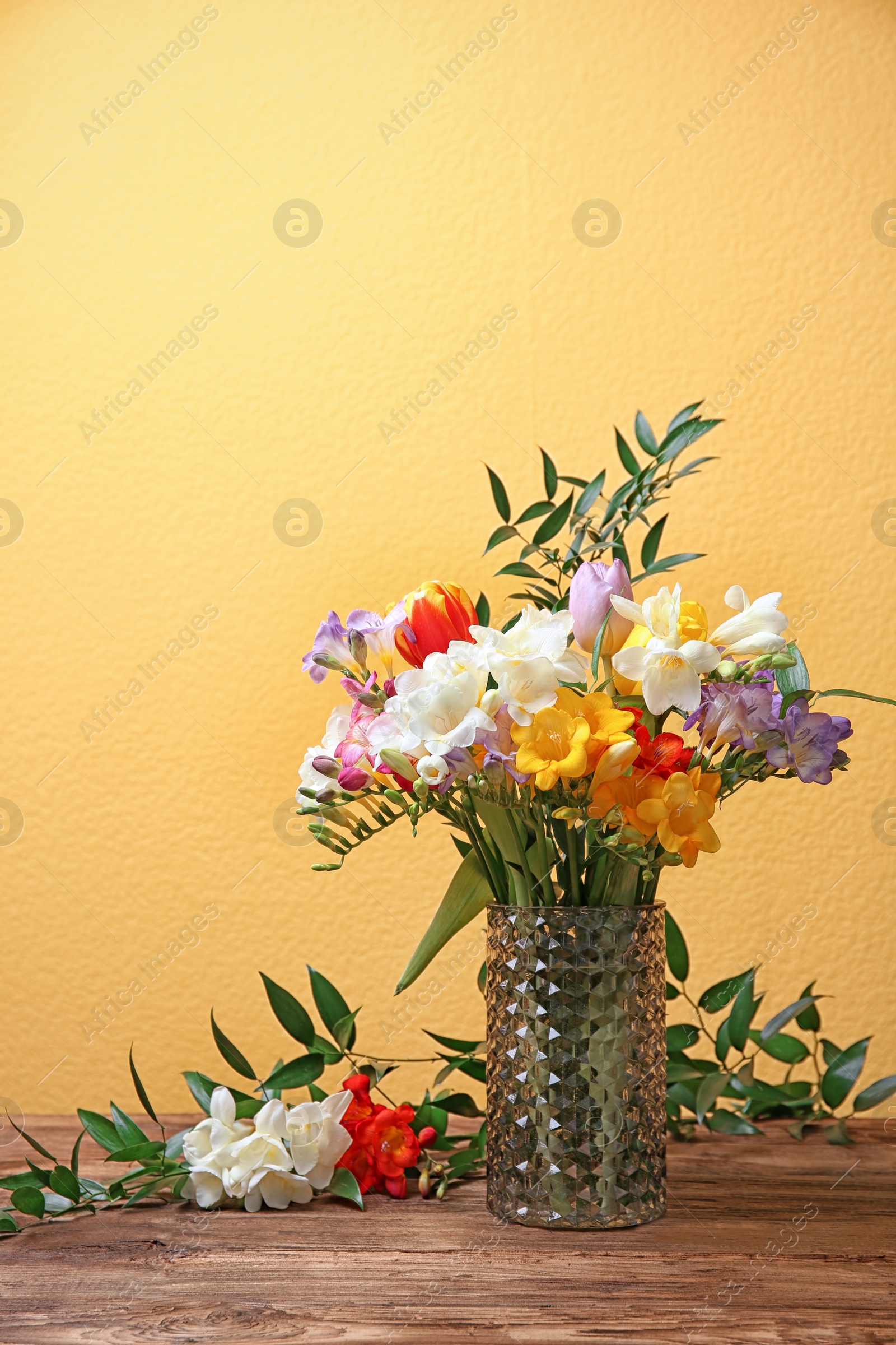 Photo of Glass vase with beautiful freesia on color background