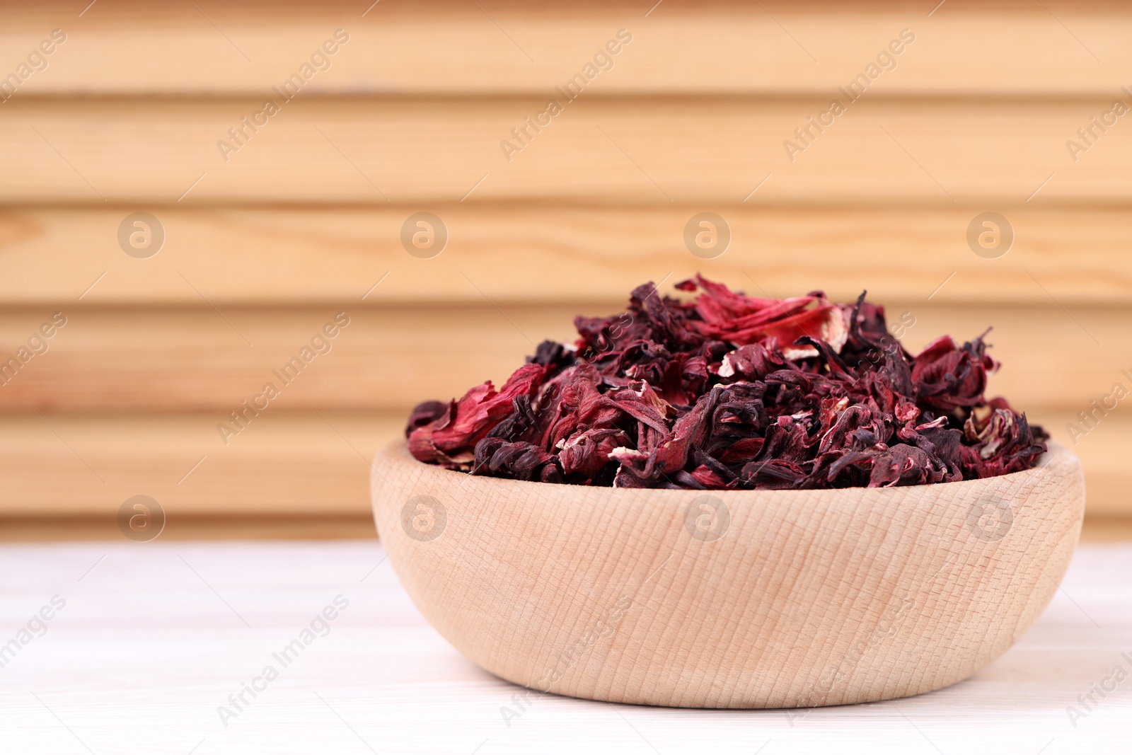 Photo of Dry hibiscus tea in bowl on white table, closeup