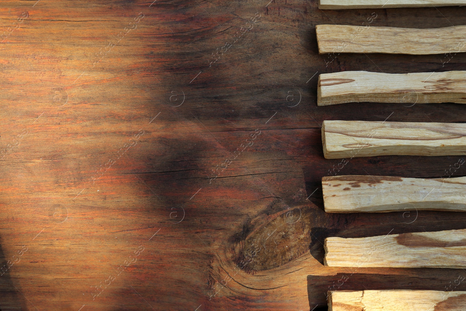 Photo of Palo santo sticks on wooden table, top view. Space for text