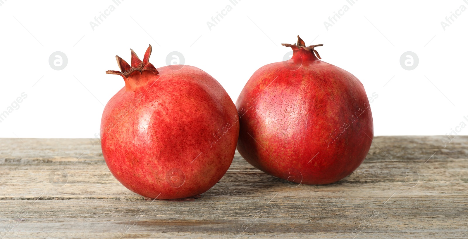 Photo of Fresh pomegranates on wooden table against white background