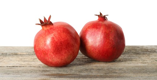 Fresh pomegranates on wooden table against white background