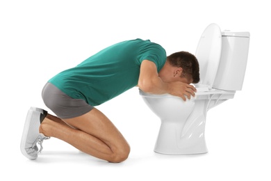 Photo of Young man vomiting in toilet bowl on white background