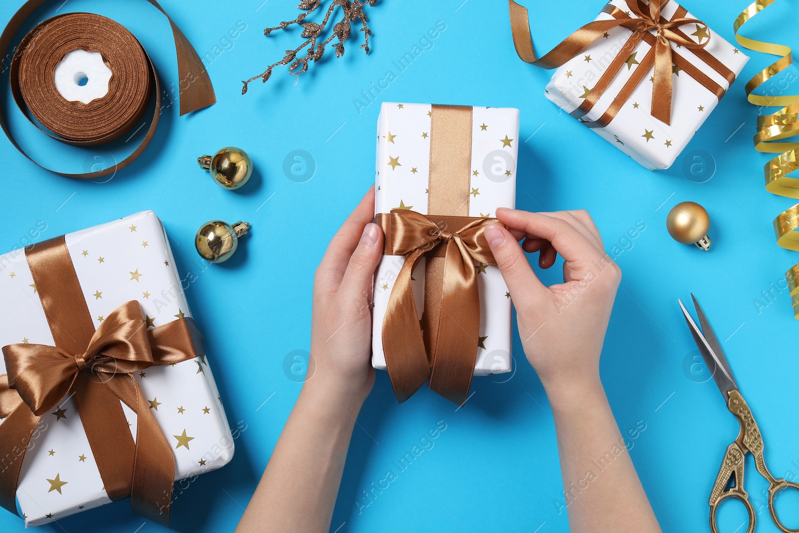 Photo of Woman with Christmas gifts on light blue background, top view