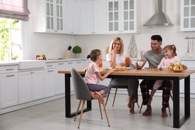 Happy family having breakfast together at table in modern kitchen