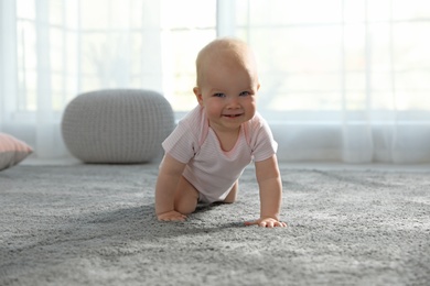 Photo of Cute little baby crawling on soft carpet indoors