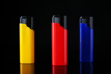 Photo of Colorful plastic cigarette lighters on black background, closeup