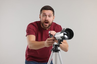 Photo of Surprised astronomer with telescope on light grey background
