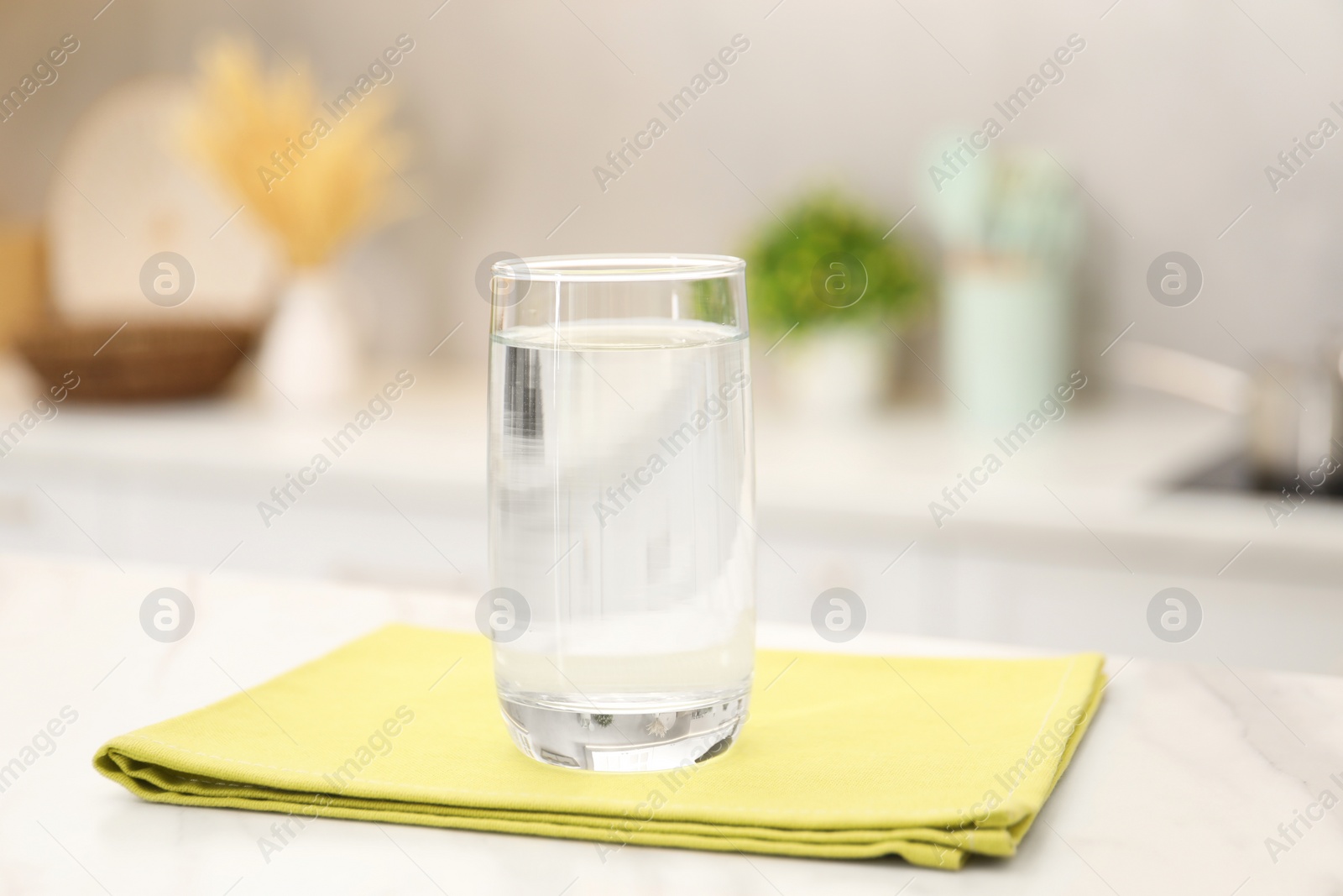 Photo of Glass with clear water on white marble table in kitchen