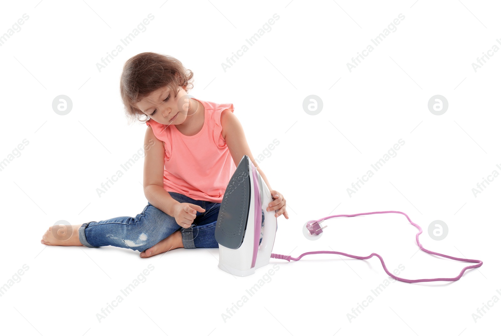 Photo of Little girl playing with iron on white background. Danger at home