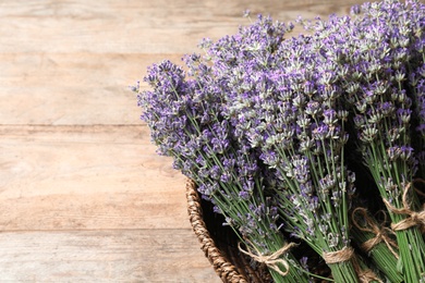 Photo of Fresh lavender flowers in basket on wooden table, closeup. Space for text