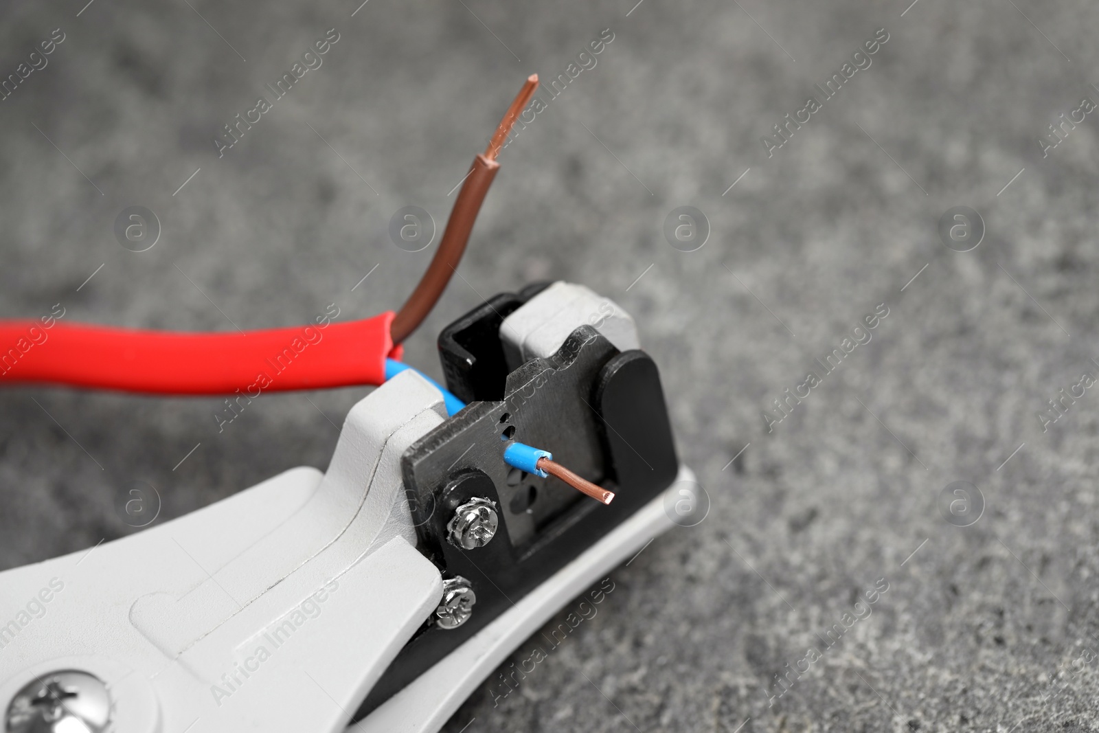 Photo of Cutters and stripped wire on light gray textured table, closeup. Space for text