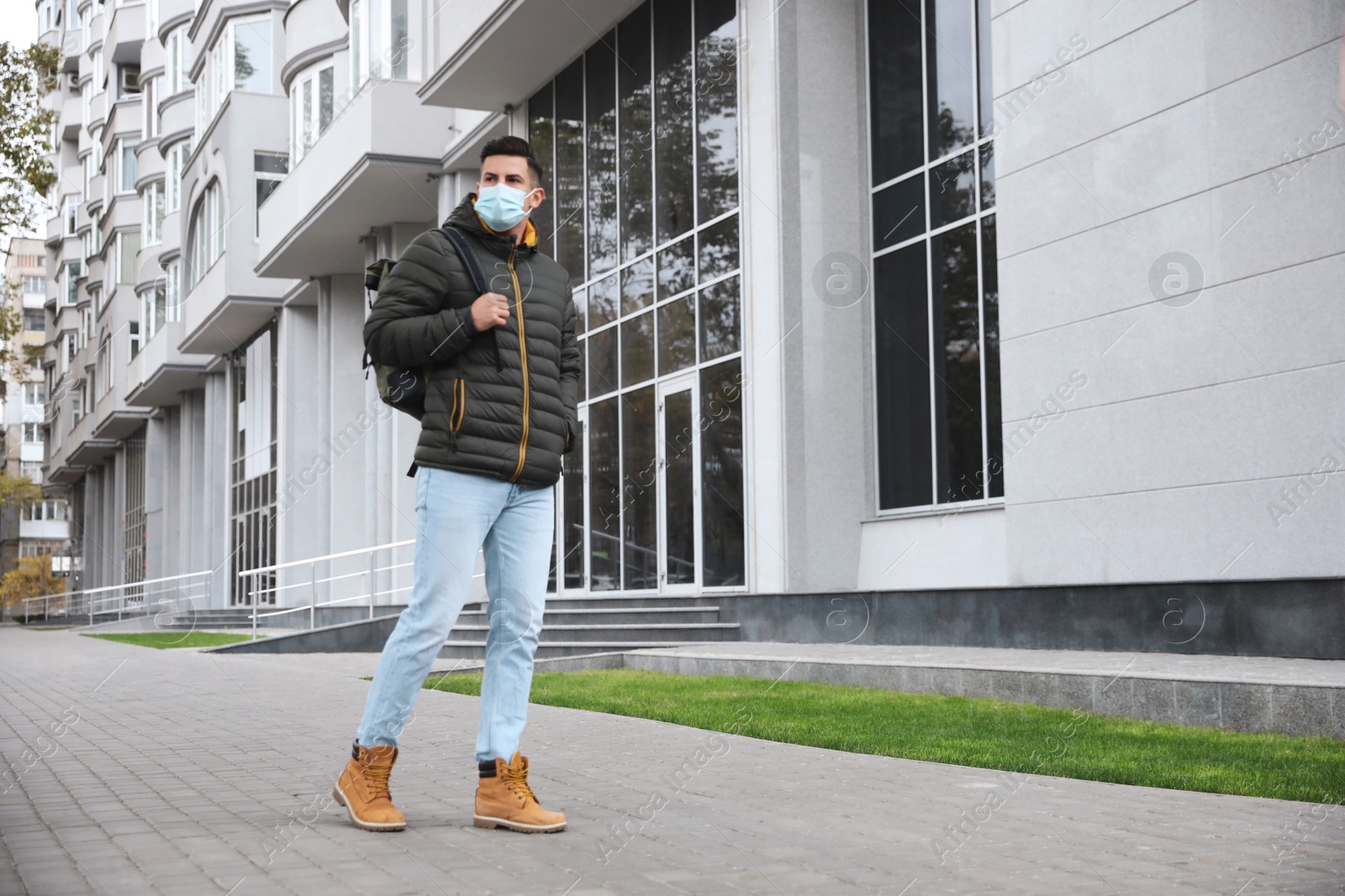 Photo of Man in medical face mask walking outdoors. Personal protection during COVID-19 pandemic