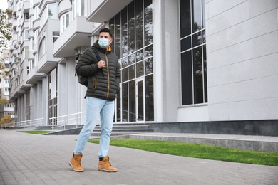 Photo of Man in medical face mask walking outdoors. Personal protection during COVID-19 pandemic