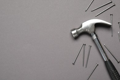 Hammer and metal nails on grey background, top view. Space for text