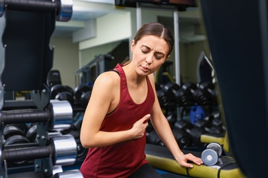 Photo of Young woman having heart attack in gym