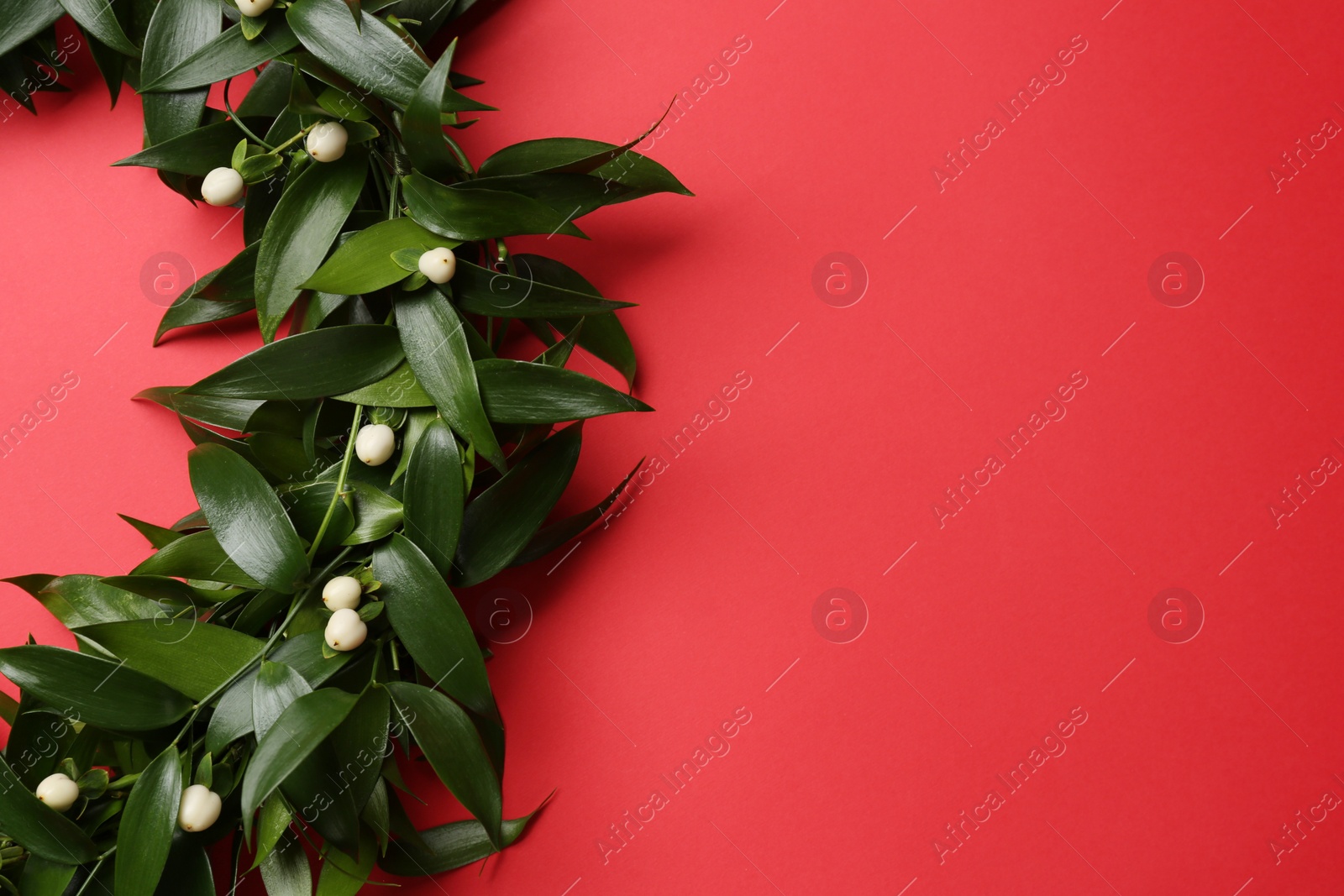 Photo of Beautiful handmade mistletoe wreath on red background. Space for text