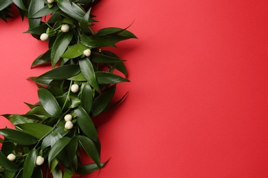 Photo of Beautiful handmade mistletoe wreath on red background. Space for text