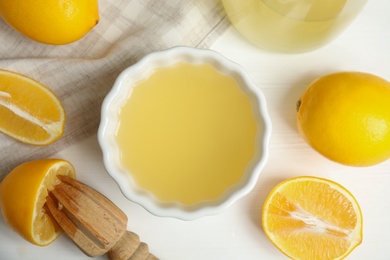 Photo of Freshly squeezed lemon juice on white wooden table, flat lay