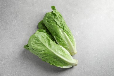 Fresh green romaine lettuces on light grey table, top view