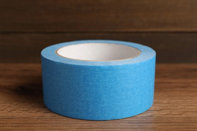 Photo of Roll of light blue adhesive tape on wooden table, closeup