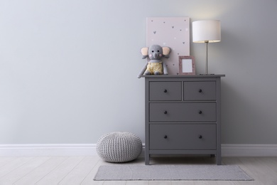Modern grey chest of drawers near light wall in child room, space for text. Interior design