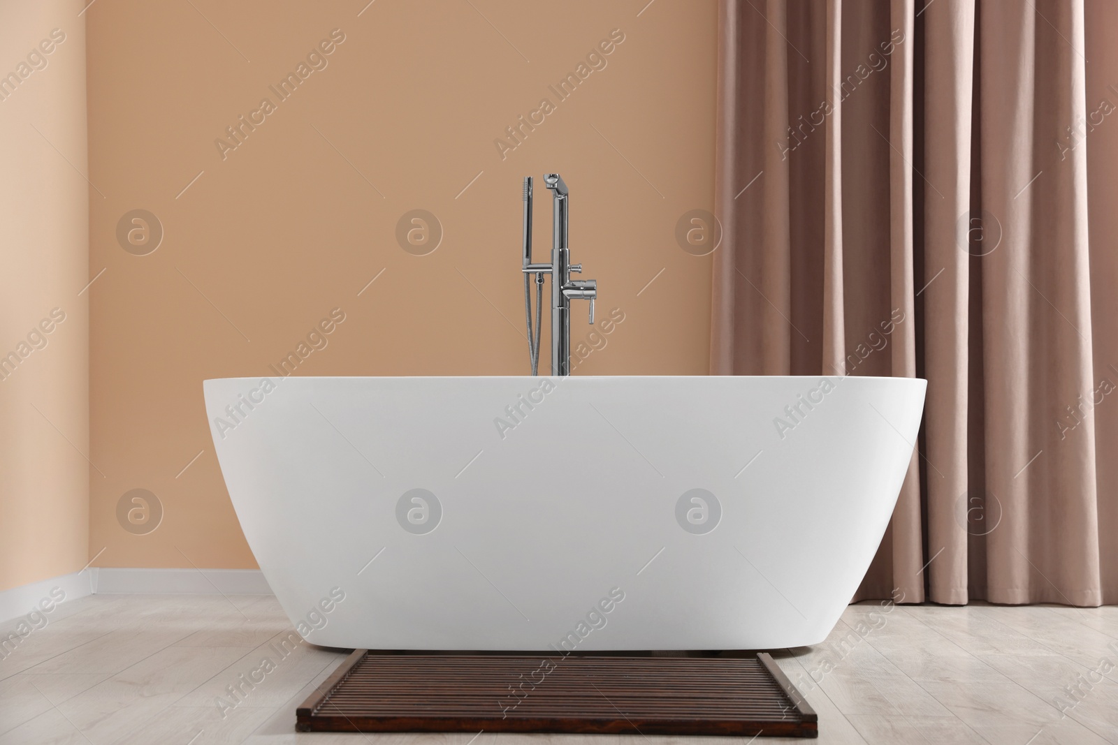 Photo of Stylish bathroom interior with ceramic tub near beige curtains