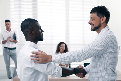 Photo of Boss introducing new employee to coworkers in office
