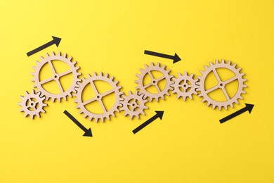 Photo of Business process organization and optimization. Scheme with wooden figures and arrows on yellow background, top view