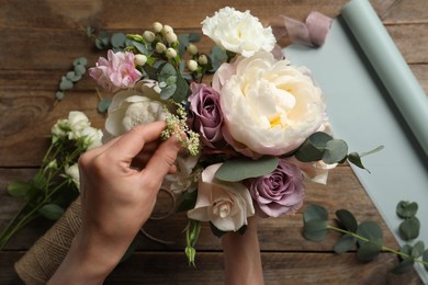 Florist creating beautiful bouquet at table, top view