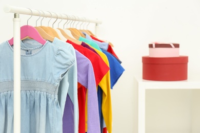 Different child's clothes hanging on rack indoors. Space for text