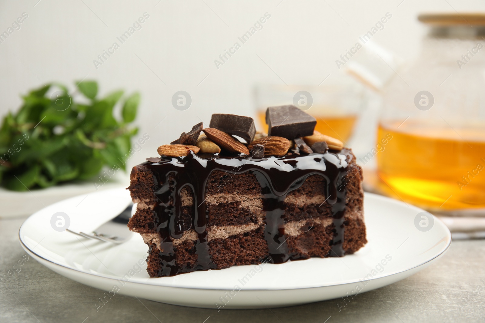 Photo of Piece of tasty homemade chocolate cake with nuts on grey table, closeup