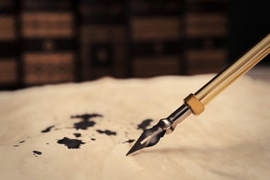 Photo of Fountain pen and vintage parchment with ink stains, closeup. Space for text