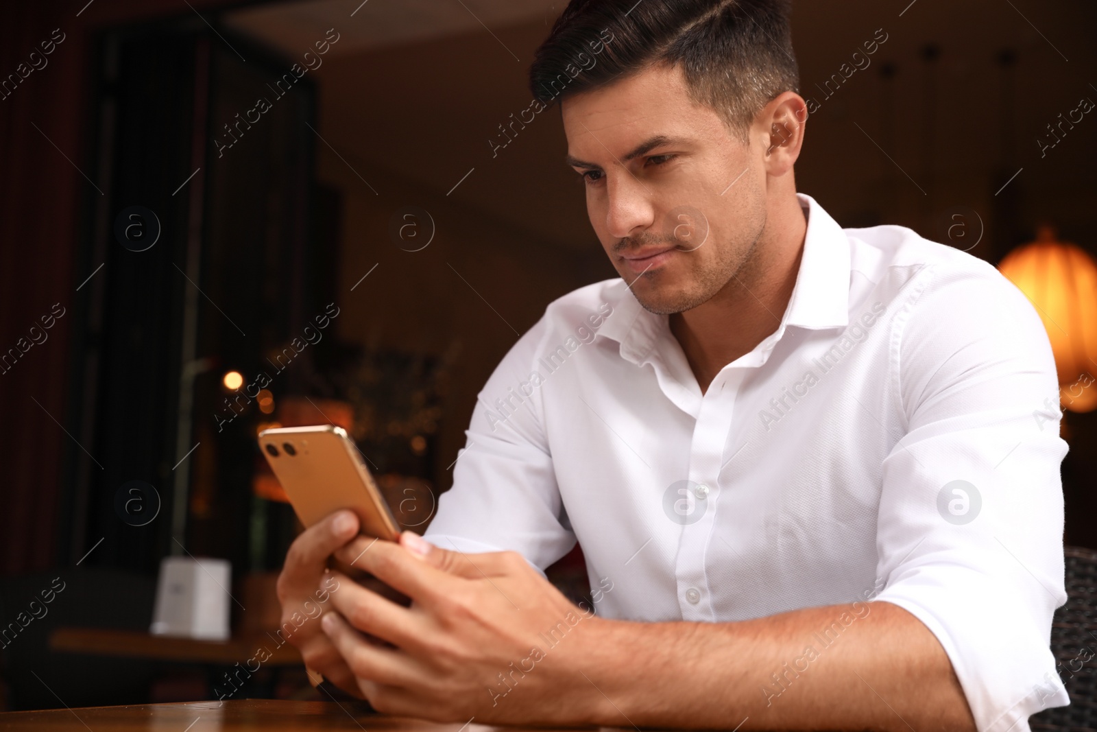 Photo of Man unlocking smartphone with facial scanner in cafe. Biometric verification